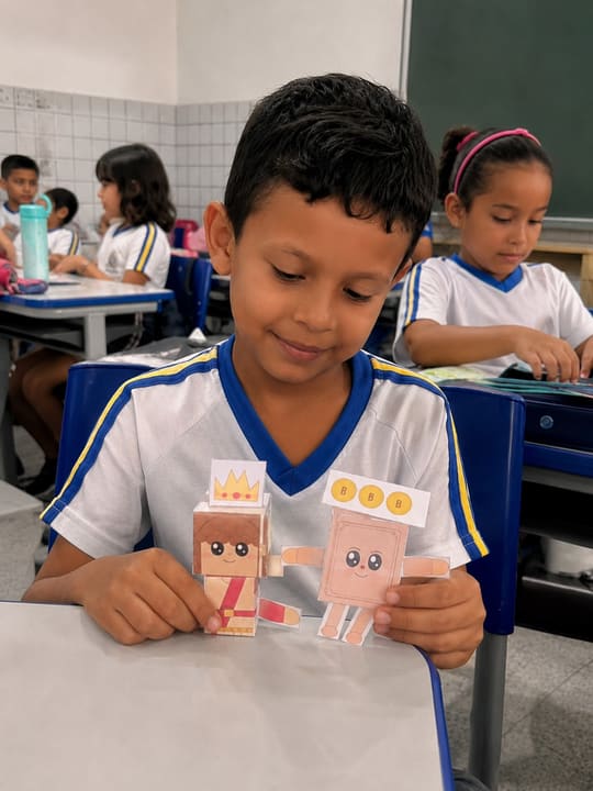 Menino de uniforme escolar com o Rei Davi e o Biblinha em cima da carteira